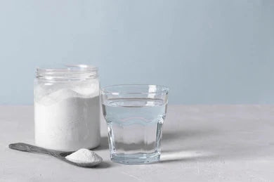 Collagen Protein in spoon and jar next to glass of water