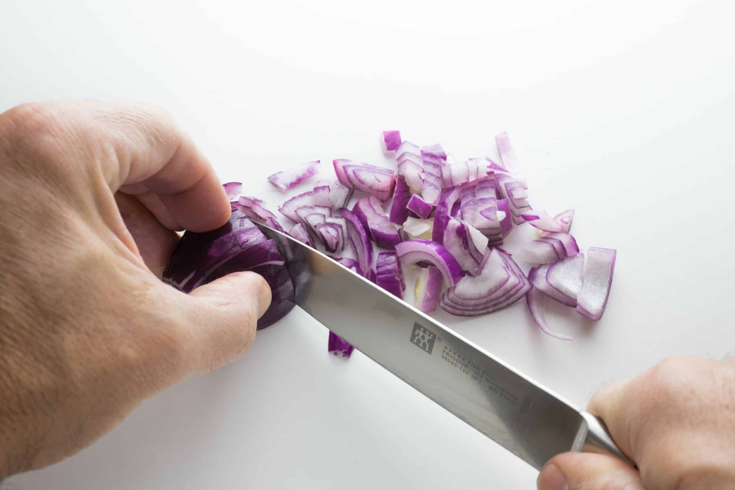 Close up of hands dicing onion